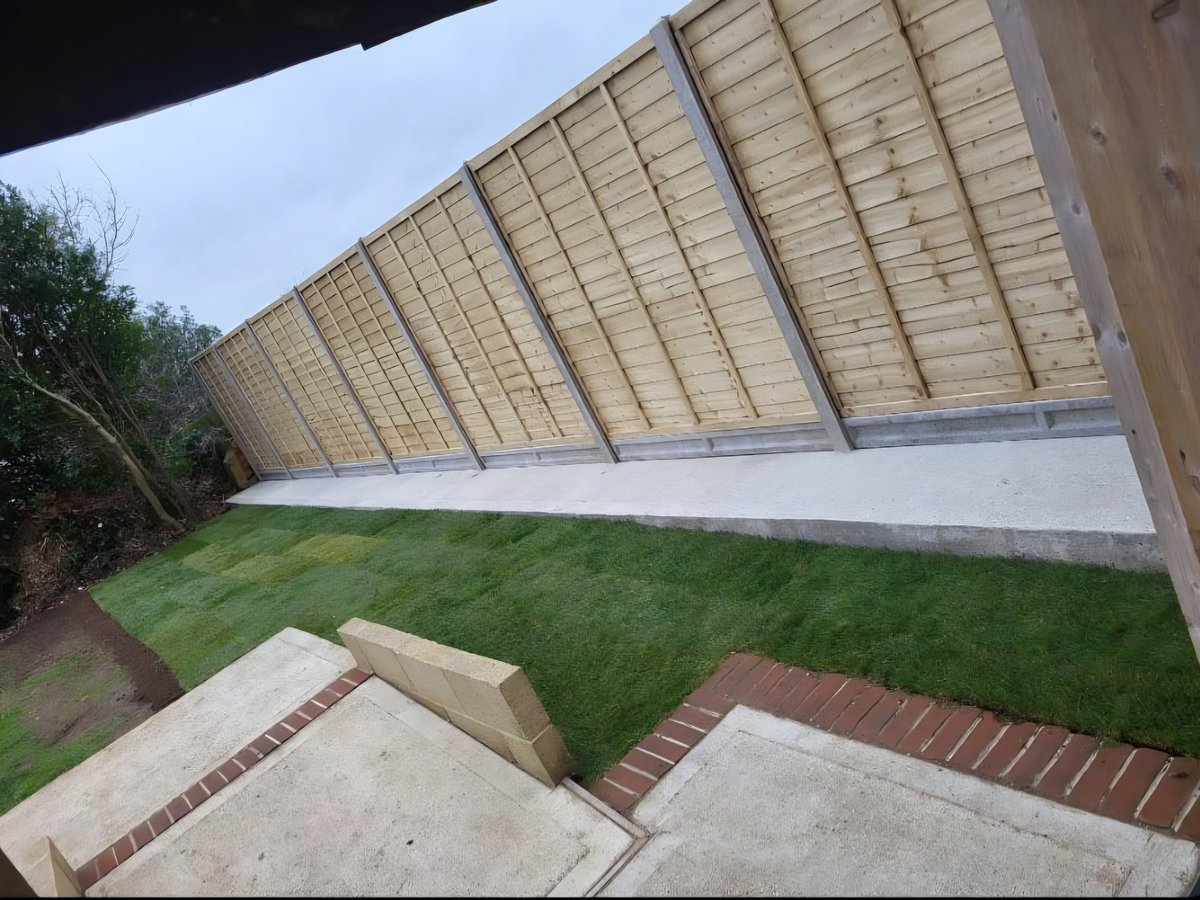 Modern architectural structure with large angled roof panels over green lawn and brick pathway