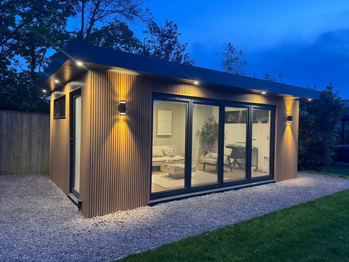 Contemporary garden retreat with corrugated metal siding and warm uplighting