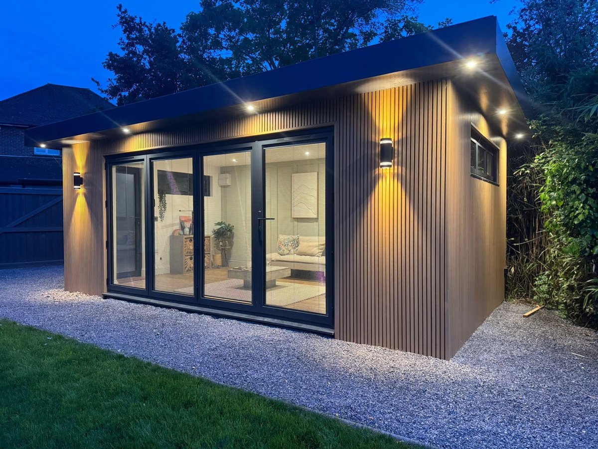 Modern garden studio with corrugated metal siding and warm lighting at dusk